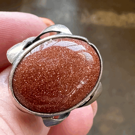 Goldstone set in fanciful floral stamped silver band sz. 7.5